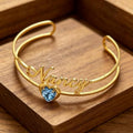 The Birthstone Charm Bangle displayed elegantly in a wooden jewellery box.
