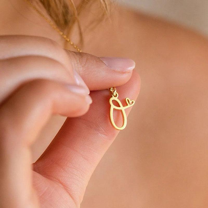 Close-up of a woman delicately holding the personalised Everlasting Love Necklace, showcasing the gold-plated letter pendant.
