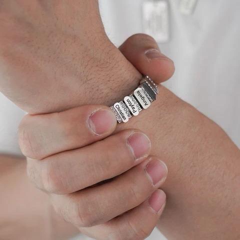 Man modelling the silver Forever Family Bracelet on his wrist, featuring personalised family name charms.

